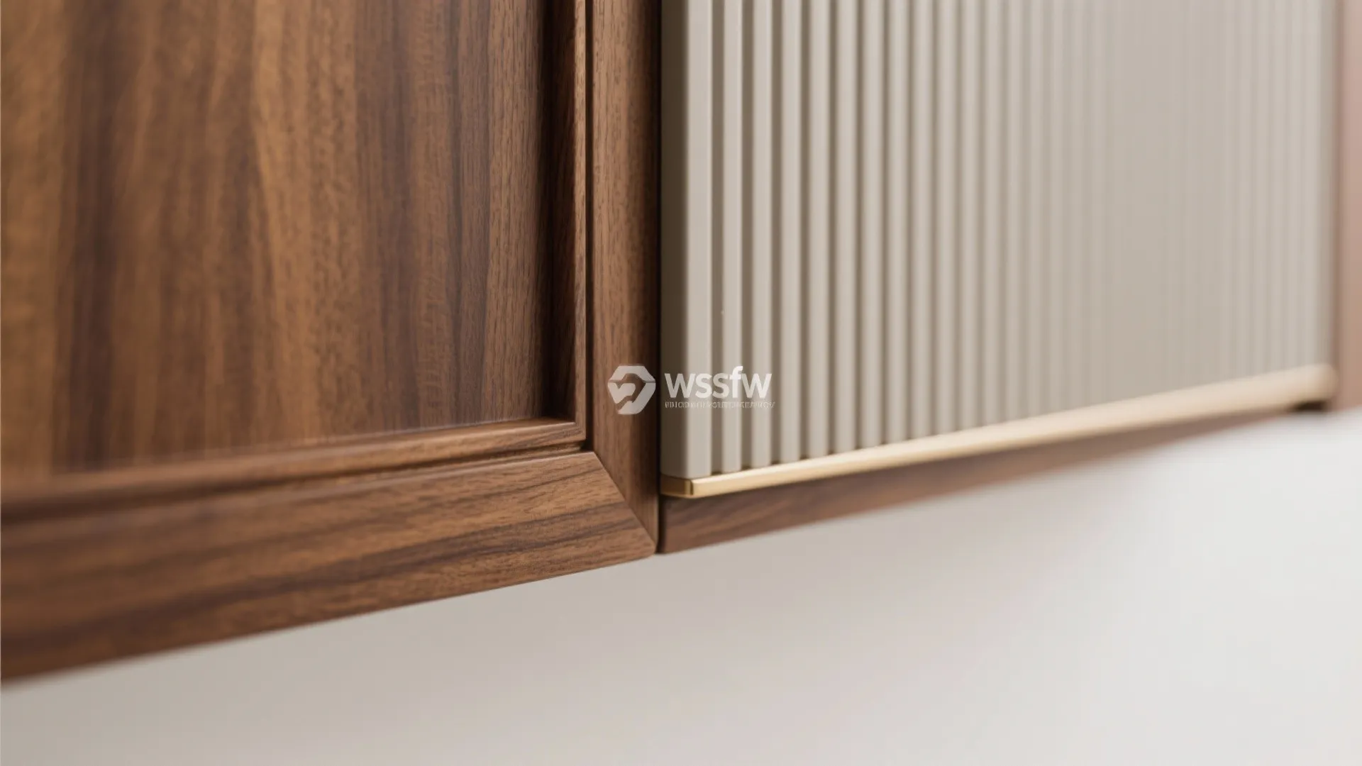 Close up of wooden cabinet door with vertical white wall panel and gold metal edge detail