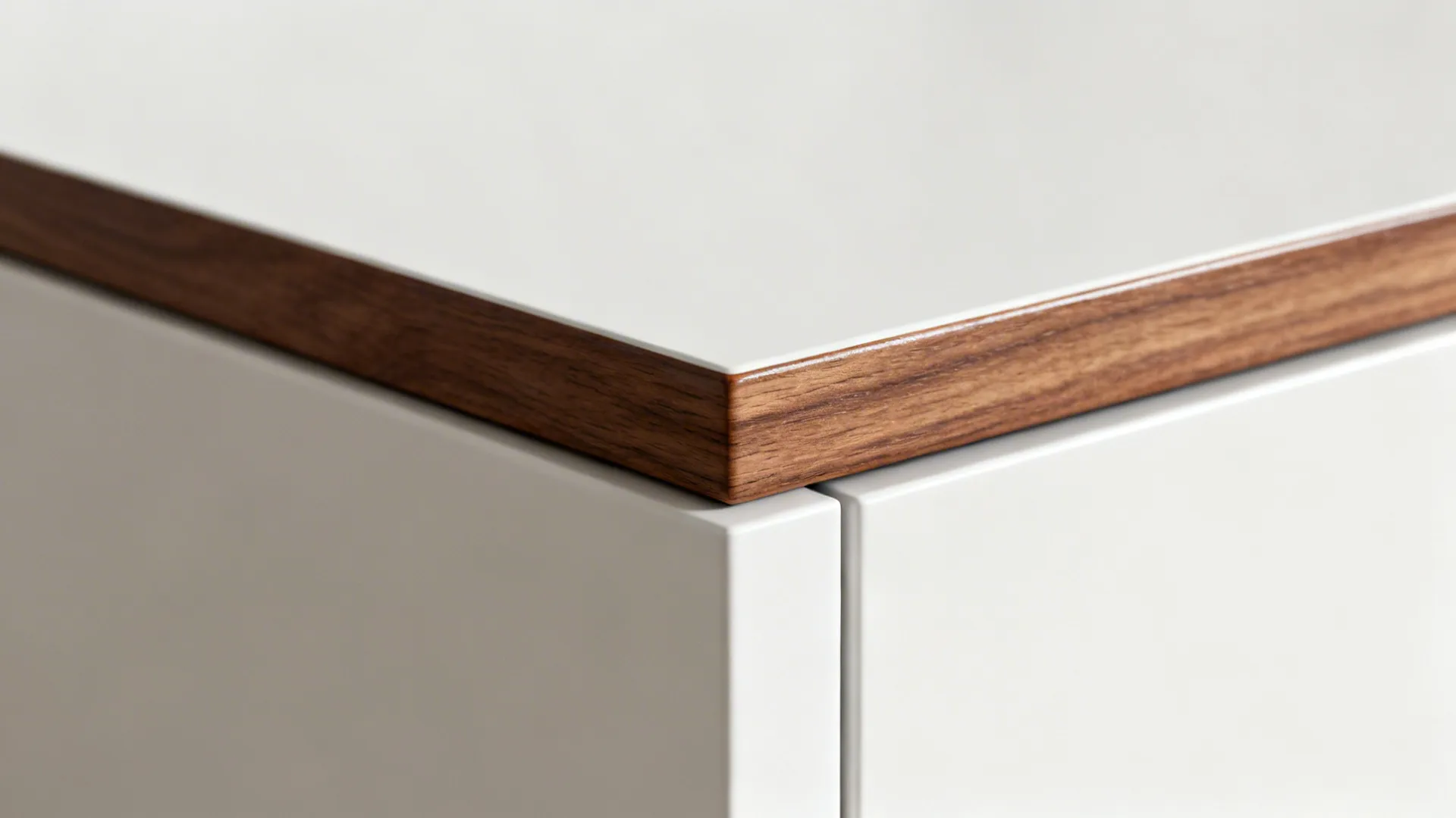 Close-up of walnut trim meeting a matte white cabinet with smooth varnished finish.