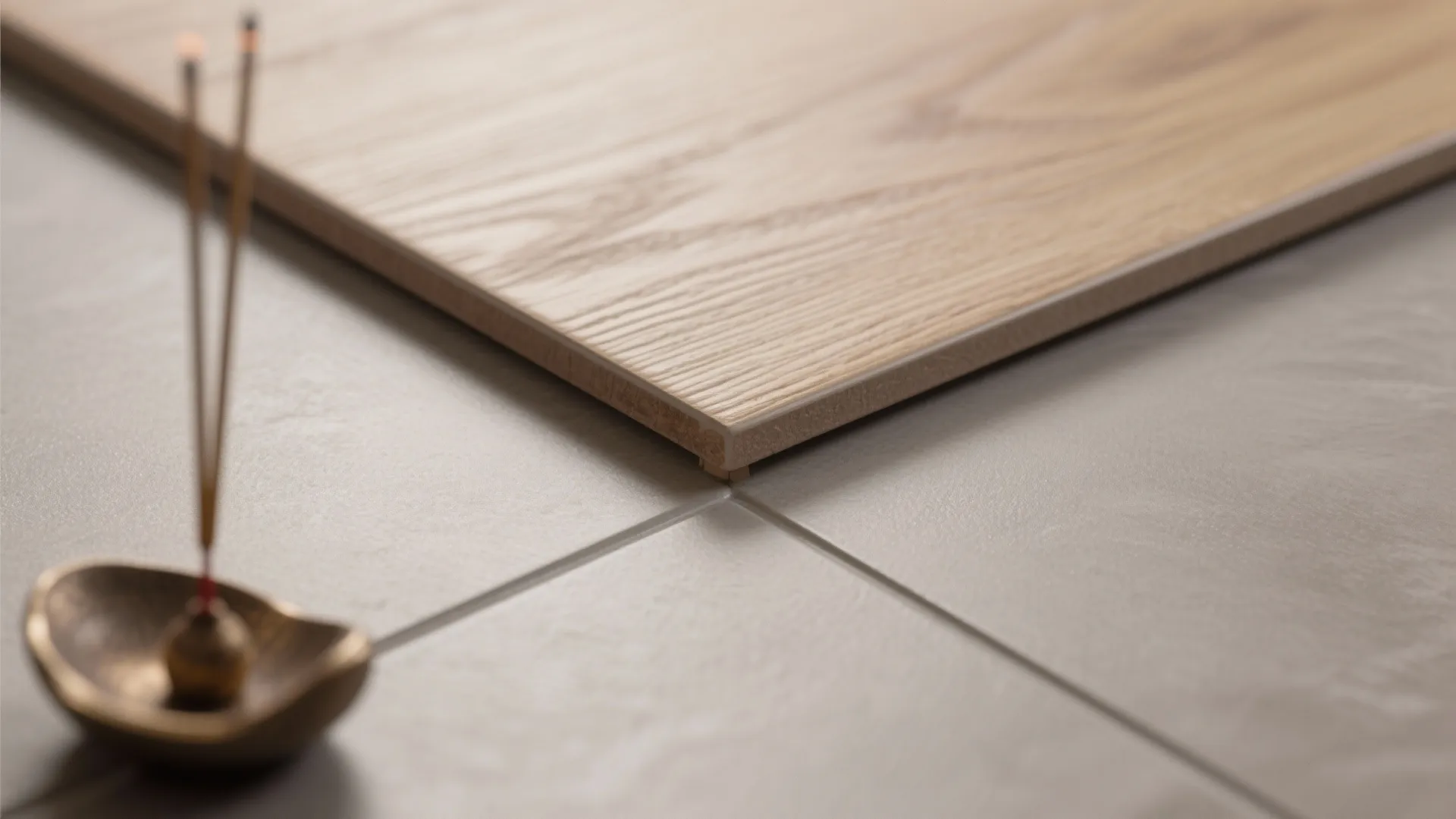 Wood pattern tile sitting on grey floor next to burning incense sticks in small bowl