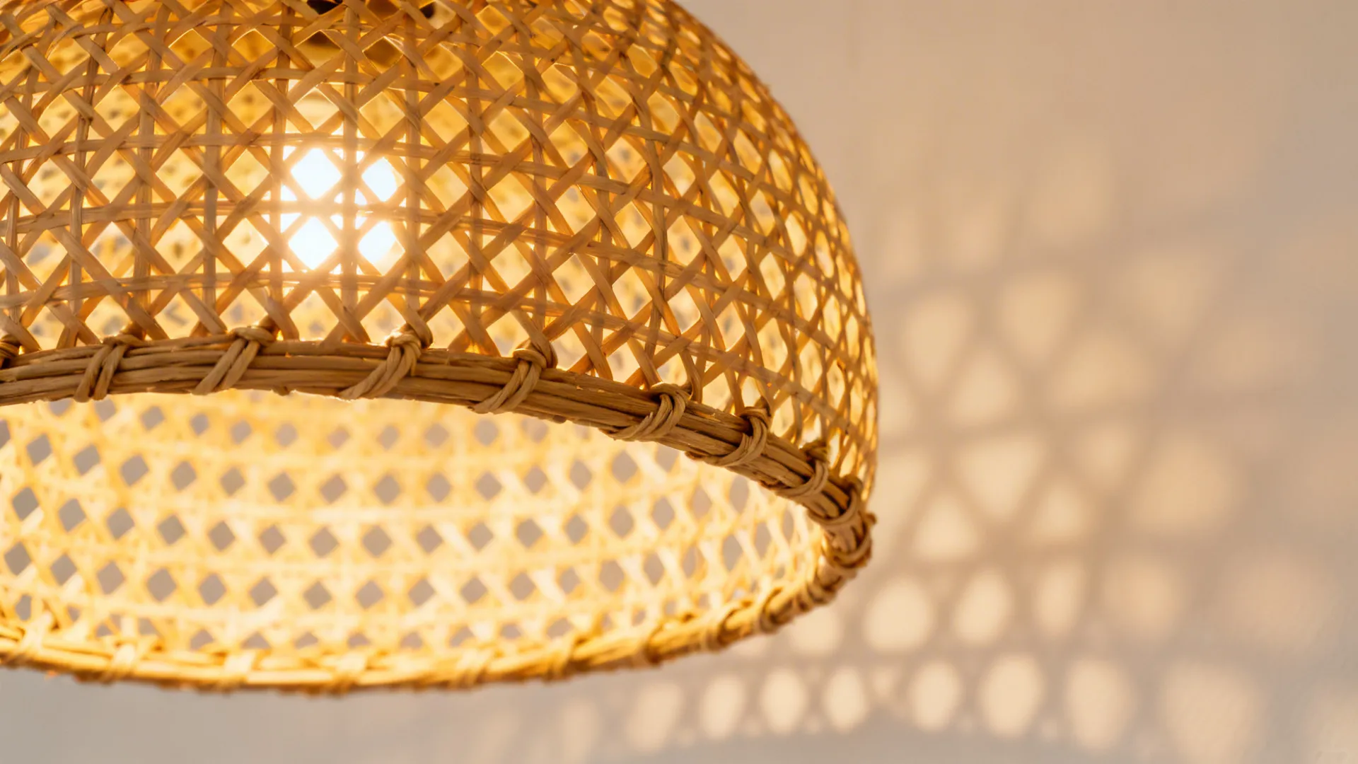 Close up of a woven ceiling light made of wood casting warm shadows on the wall