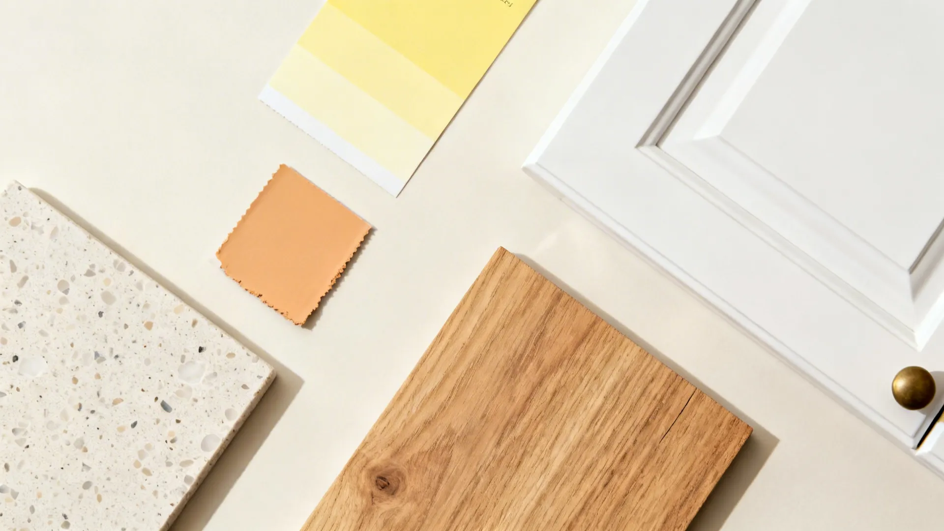 Flat lay with buttery yellow and ochre swatches, oak, terrazzo, and white cabinet sample.