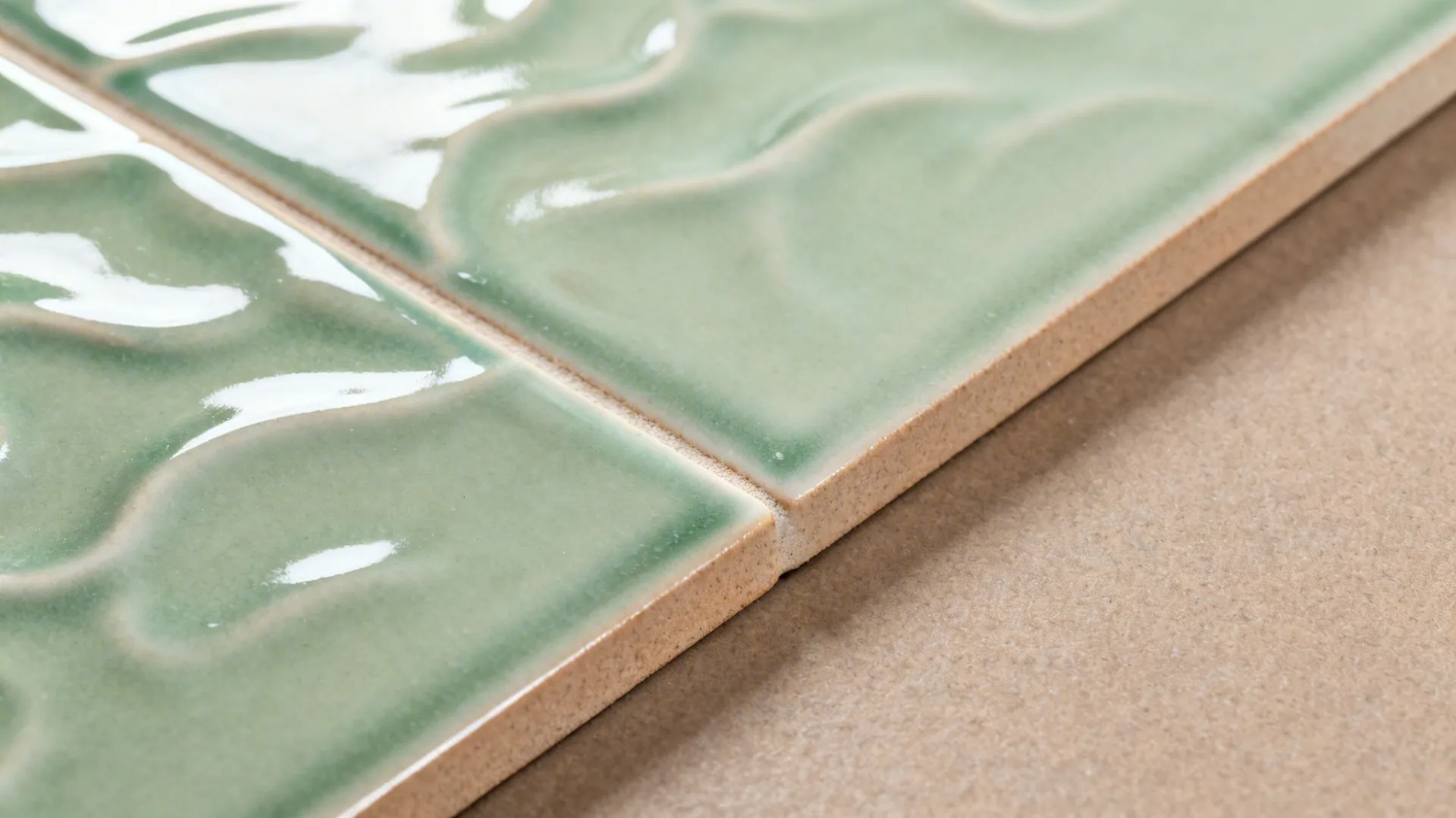 Macro of rippled glossy zellige-look tile beside honed porcelain floor.
