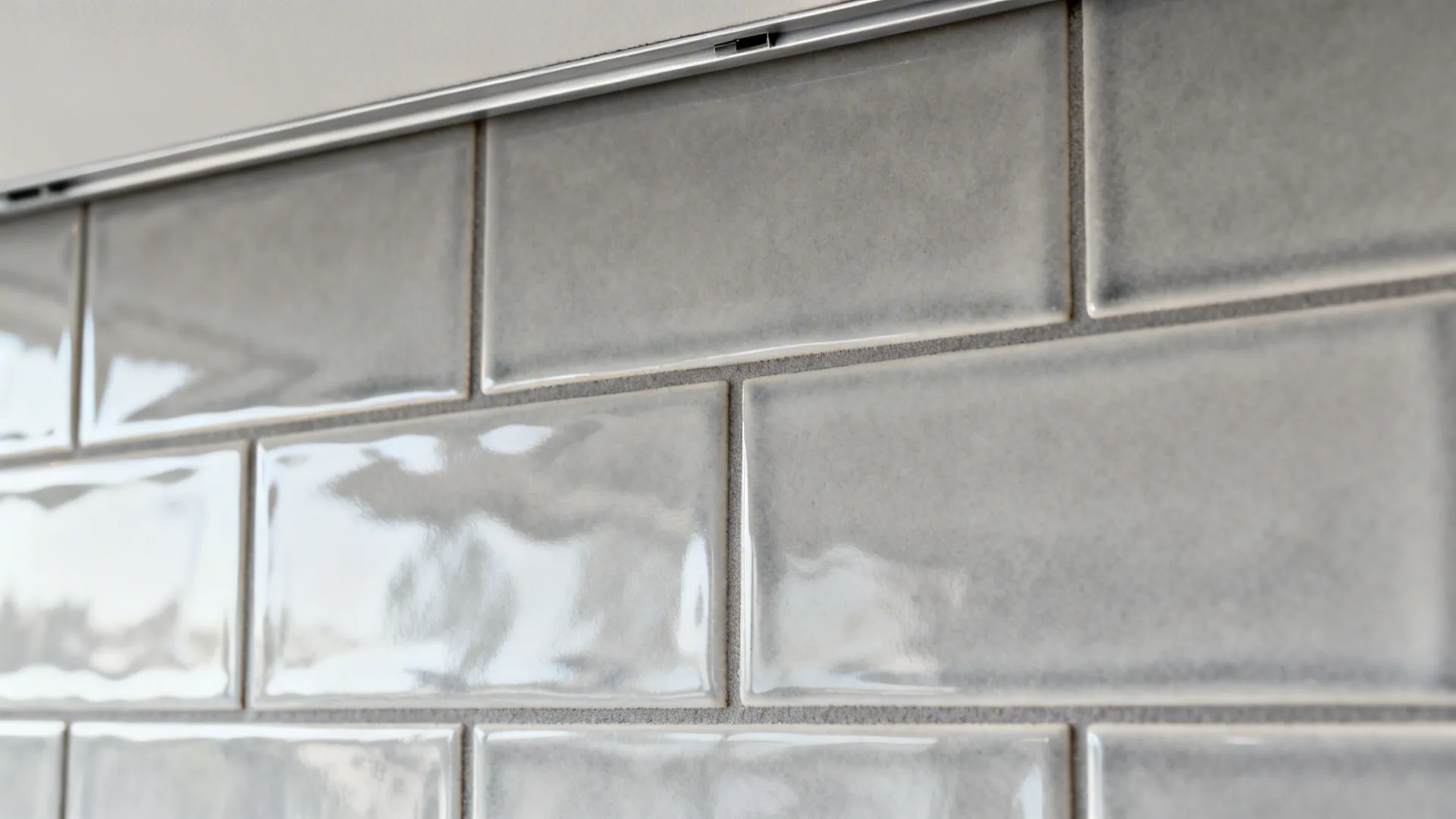 Close-up of soft grey zellige-style tile with subtle glaze variation and matching grout.