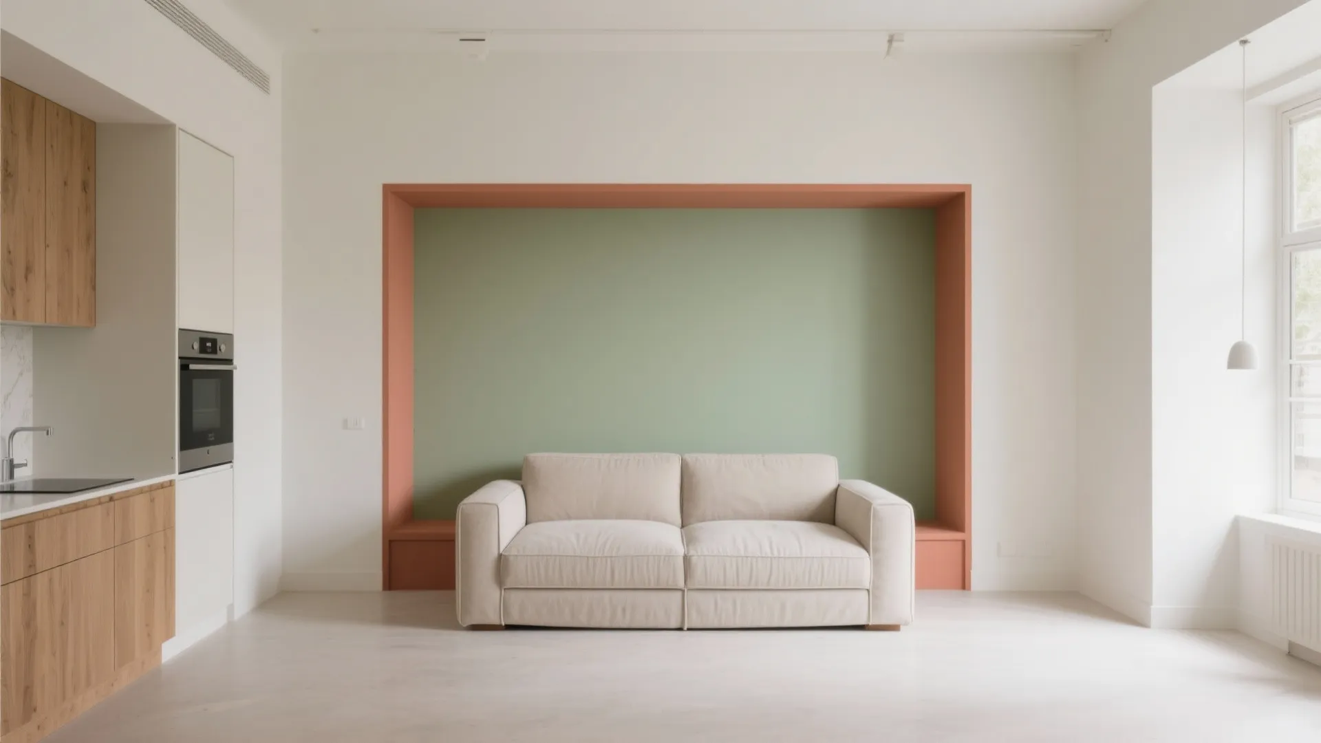 Minimalist living room with beige sofa against a green and pink wall with kitchen cabinets