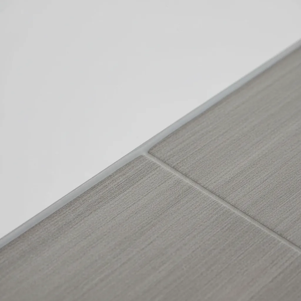 Close view of bathroom baseboard with waterproof caulking at tile floor joint