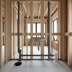 Wooden frame house construction showing metal sink gray water pipes white tubes and concrete floor