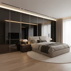 Modern bedroom with a beige bed, wood floor, round rug, and large black mirrored cabinet