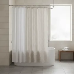 Modern white bathtub with double shower curtains hanging from a curved metal rod in bathroom