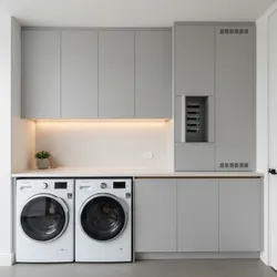 Modern laundry room with grey cabinets, white washing machines, sleek countertop, and hidden power panel