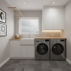 Bright laundry room with two grey washing machines white sink wooden countertop and hanging drying rack