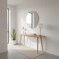 Minimalist entryway with wooden table, round mirror, table lamp, books, and a tall potted plant